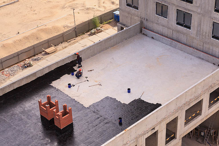 Two Workers Conduct Waterproofing Of The Roof With Bitumen. View